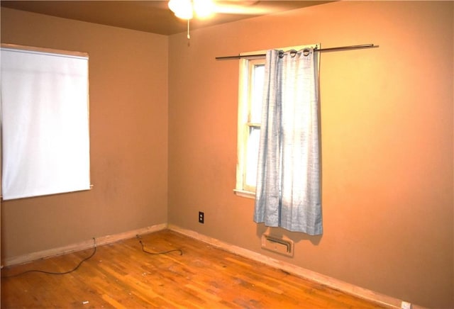 spare room featuring baseboards and wood finished floors