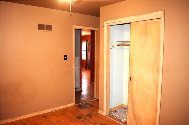 unfurnished bedroom featuring a closet, wood finished floors, visible vents, and baseboards