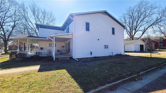 view of side of property with a lawn, a porch, and an outdoor structure