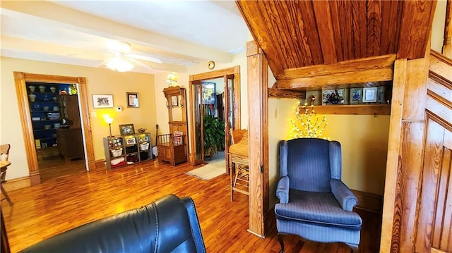 living area featuring beamed ceiling, a ceiling fan, and wood finished floors