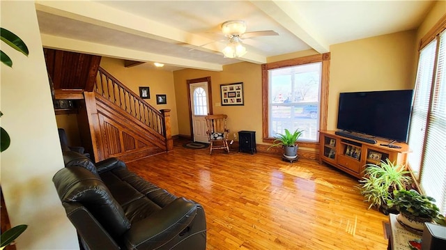 living room featuring beamed ceiling, a ceiling fan, wood finished floors, stairway, and baseboards