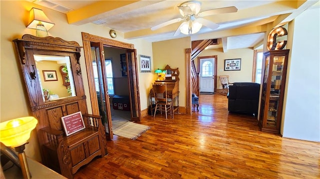 hallway with beamed ceiling, visible vents, baseboards, and wood finished floors