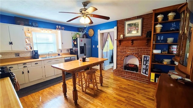 kitchen with light countertops, light wood-style flooring, stainless steel appliances, white cabinetry, and a sink