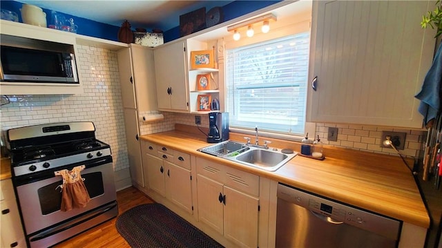 kitchen featuring wood finished floors, a sink, light countertops, appliances with stainless steel finishes, and tasteful backsplash