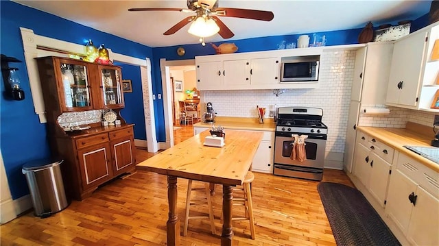 kitchen with backsplash, light wood-style floors, appliances with stainless steel finishes, white cabinets, and light countertops