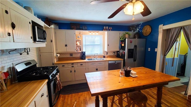 kitchen with a sink, white cabinetry, appliances with stainless steel finishes, and light countertops