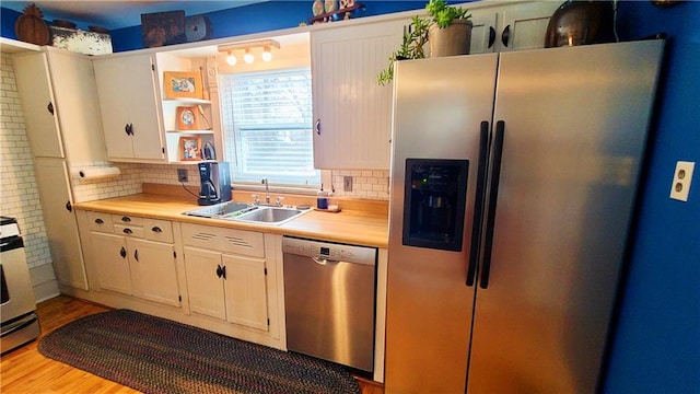 kitchen featuring backsplash, light wood-type flooring, light countertops, appliances with stainless steel finishes, and a sink