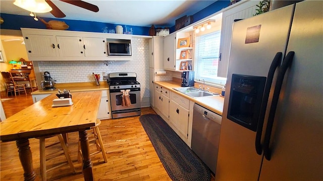 kitchen featuring a sink, light wood-style floors, appliances with stainless steel finishes, white cabinets, and light countertops