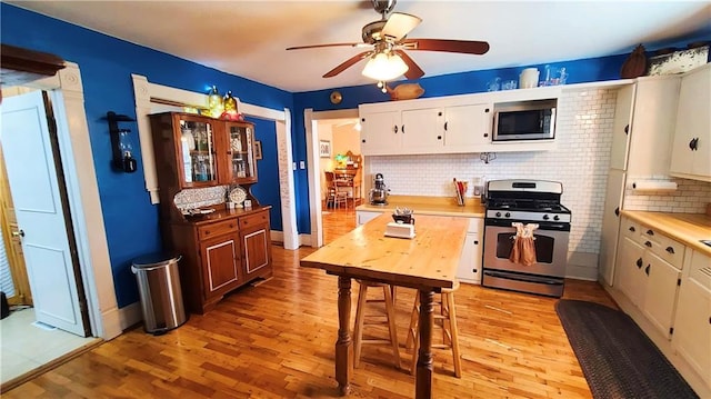 kitchen with stainless steel appliances, light wood-style flooring, decorative backsplash, and white cabinetry