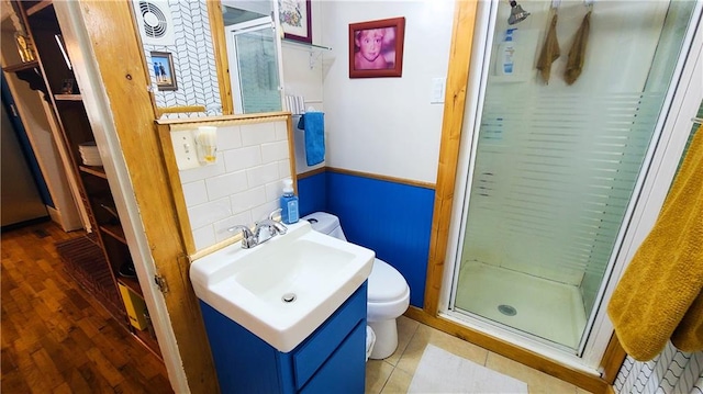 bathroom with a shower stall, toilet, vanity, and wood finished floors