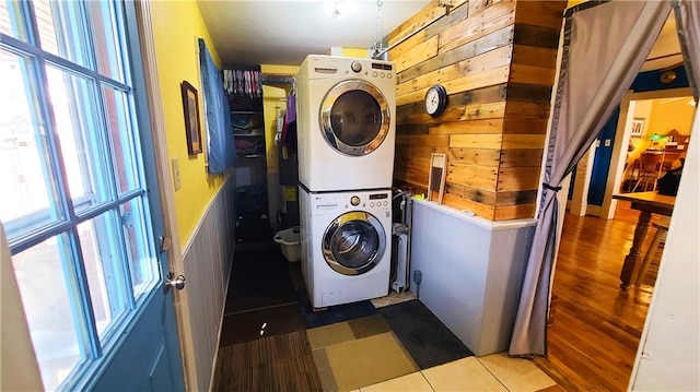 washroom featuring laundry area, stacked washer / dryer, plenty of natural light, and wood finished floors