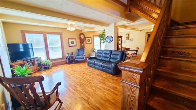 living area featuring light wood finished floors, beam ceiling, stairs, and a ceiling fan