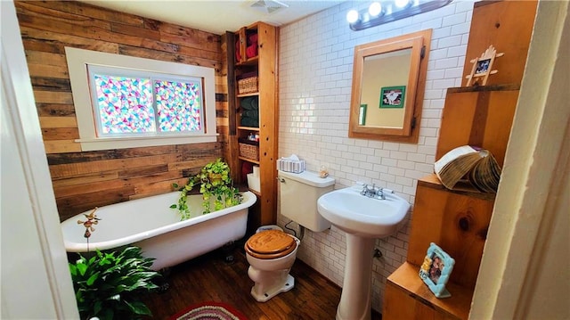 bathroom featuring wood finished floors, visible vents, a freestanding tub, wood walls, and toilet