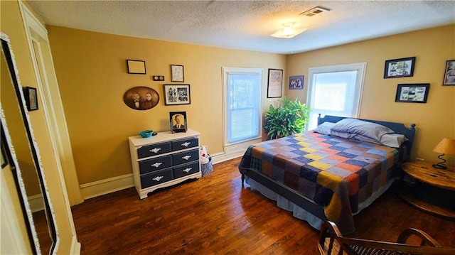 bedroom with baseboards, dark wood-style floors, visible vents, and a textured ceiling