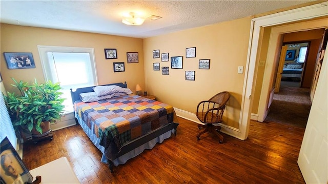 bedroom featuring baseboards, a textured ceiling, and wood finished floors