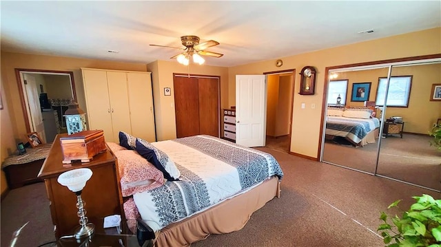 bedroom with baseboards, visible vents, two closets, and ceiling fan