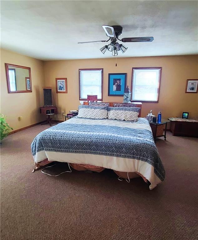 carpeted bedroom with multiple windows, baseboards, and ceiling fan