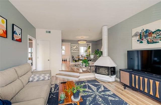 living area with a wood stove, plenty of natural light, visible vents, and wood finished floors