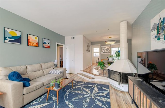 living room featuring light wood-type flooring, visible vents, and ornate columns