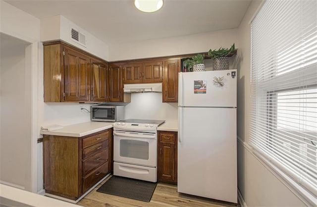 kitchen with light wood finished floors, light countertops, visible vents, white appliances, and under cabinet range hood