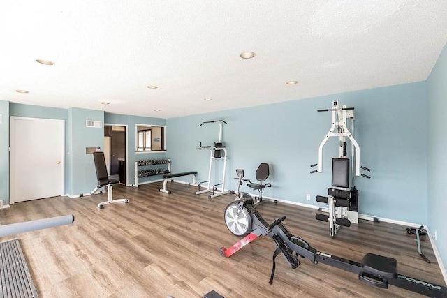 workout area featuring visible vents, baseboards, wood finished floors, a textured ceiling, and recessed lighting