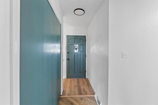 doorway to outside with visible vents, light wood-style flooring, and a textured wall