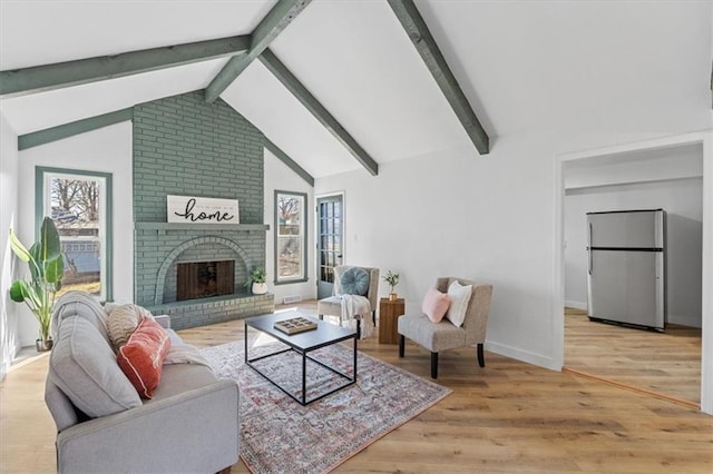 living area featuring lofted ceiling with beams, a brick fireplace, wood finished floors, and baseboards