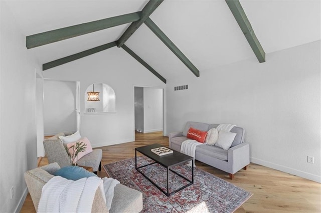 living room with visible vents, vaulted ceiling with beams, baseboards, and wood finished floors