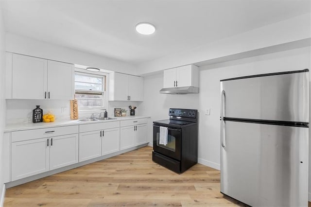 kitchen featuring black / electric stove, freestanding refrigerator, a sink, under cabinet range hood, and white cabinetry