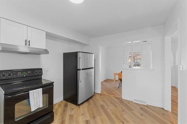 kitchen with under cabinet range hood, light wood-type flooring, freestanding refrigerator, black electric range, and white cabinetry