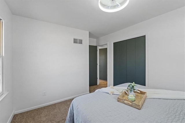 carpeted bedroom with baseboards, visible vents, and a closet