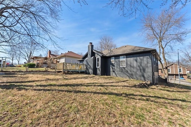 rear view of property featuring a deck, board and batten siding, a yard, and fence