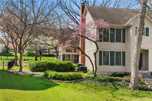 view of home's exterior featuring a yard, a shingled roof, central air condition unit, and a chimney