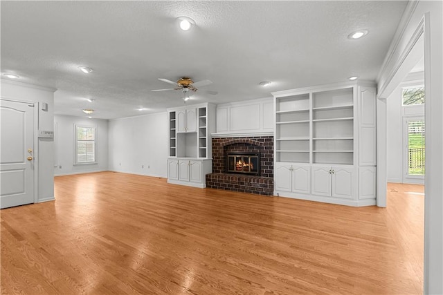 unfurnished living room with light wood finished floors, a textured ceiling, and ceiling fan