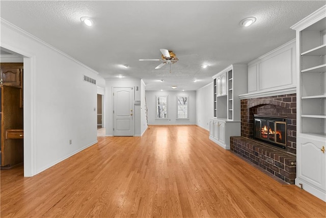 unfurnished living room with baseboards, light wood-type flooring, a ceiling fan, visible vents, and a brick fireplace