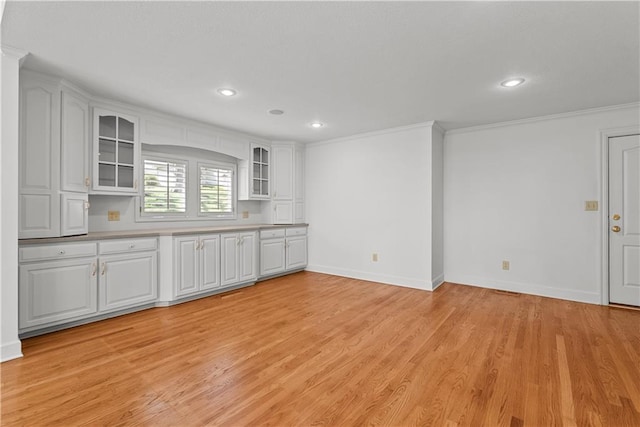 kitchen with ornamental molding, white cabinets, light wood finished floors, and glass insert cabinets