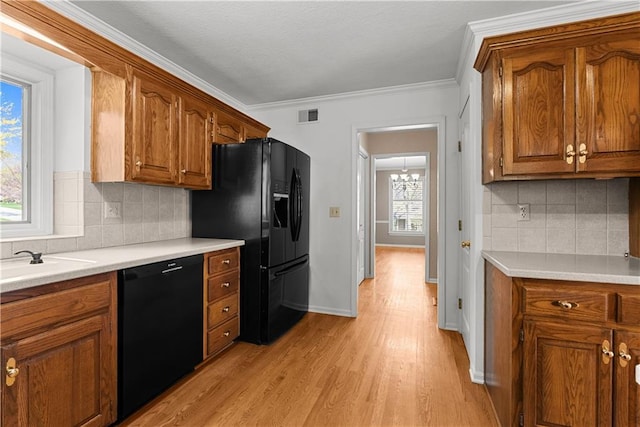 kitchen featuring visible vents, a sink, brown cabinetry, black appliances, and light wood-style flooring