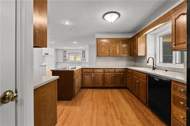 kitchen with light wood-style flooring, a peninsula, brown cabinetry, black appliances, and light countertops