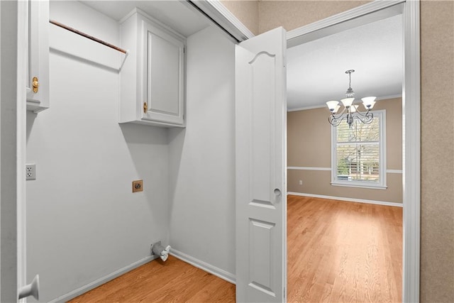clothes washing area with baseboards, an inviting chandelier, hookup for an electric dryer, light wood finished floors, and cabinet space