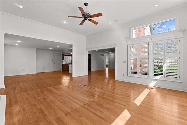 unfurnished living room with ornamental molding, light wood-style flooring, a ceiling fan, and a healthy amount of sunlight
