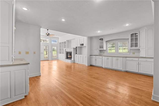unfurnished living room with light wood-style floors, ceiling fan, a glass covered fireplace, and recessed lighting