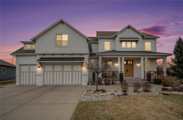 modern inspired farmhouse featuring covered porch, concrete driveway, an attached garage, board and batten siding, and a standing seam roof