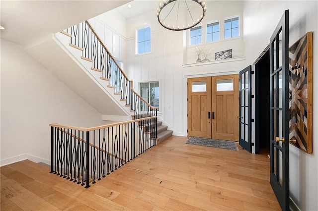 entrance foyer with stairway, a towering ceiling, hardwood / wood-style flooring, and baseboards