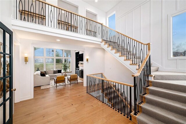 stairs with a decorative wall, a high ceiling, and wood finished floors