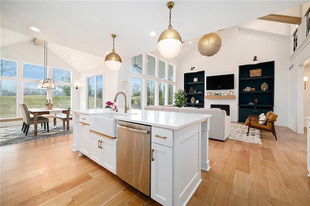 kitchen featuring a brick fireplace, a sink, light wood-style flooring, and stainless steel dishwasher