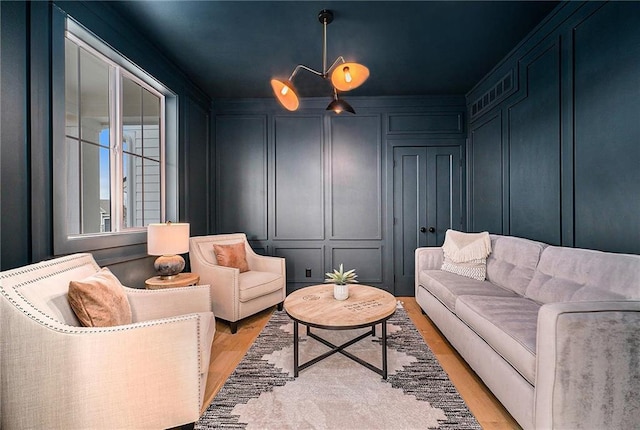 living room with ornamental molding, light wood-type flooring, and a decorative wall