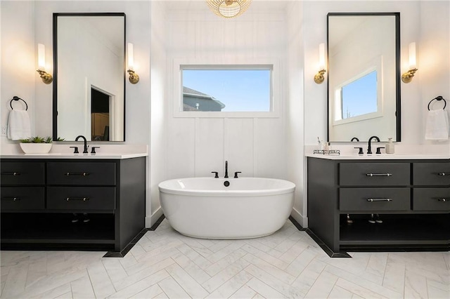 full bath with a freestanding tub, two vanities, and a sink