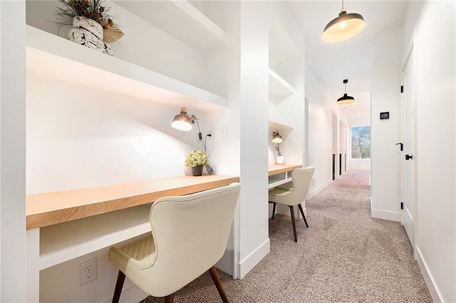 carpeted office space featuring built in study area, a towering ceiling, and baseboards