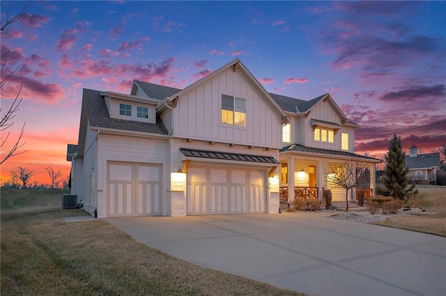 modern farmhouse featuring central air condition unit, a garage, covered porch, concrete driveway, and board and batten siding