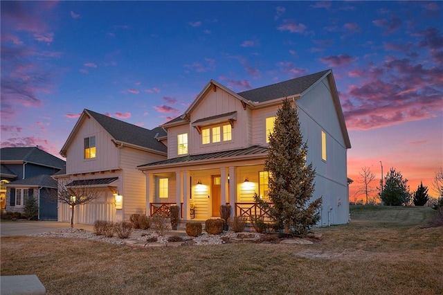 view of front of home featuring an attached garage, covered porch, concrete driveway, a yard, and a standing seam roof